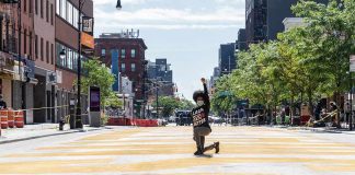 One of America’s Largest Black Parades Erupts Into Chaos Person kneeling on painted city street raising fist