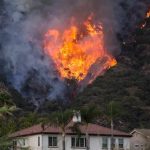 Wildfire burning on a hillside near homes