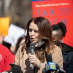 Woman speaking into a microphone at a rally