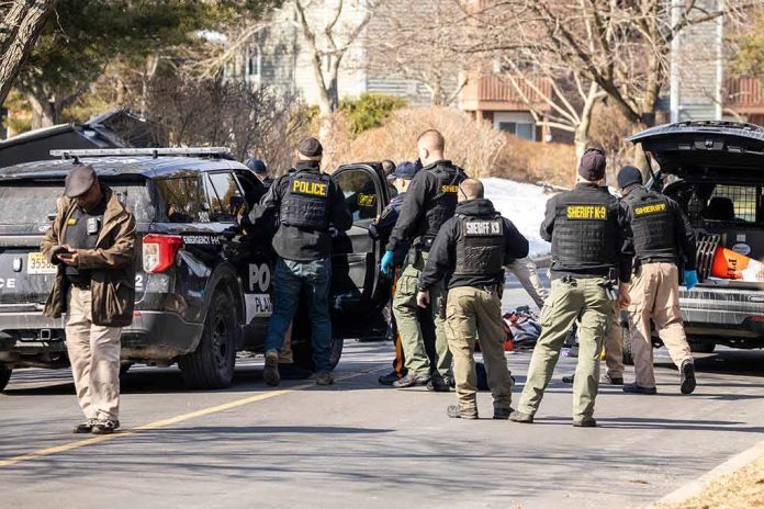 Police and sheriff officers gather around vehicles on a suburban street