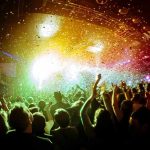 crowd at indoor concert with confetti and bright stage lights