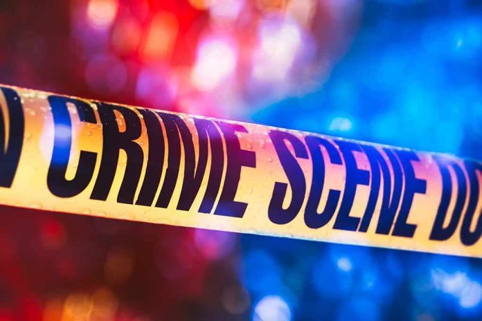 shutterstock_1019899543-1 Crime scene tape with blurred emergency lights in background