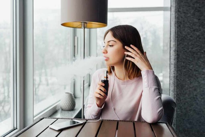 woman vaping by a window