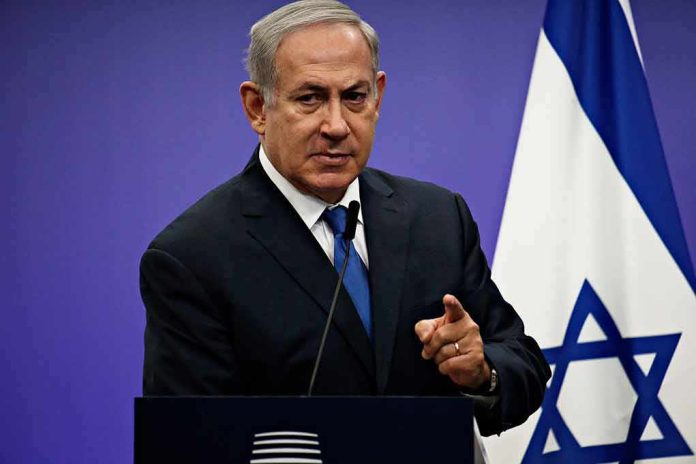 shutterstock_1042782061-1 man in suit speaking at a podium with an Israeli flag