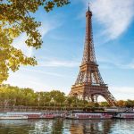 Eiffel Tower in Paris with boats on the river and green trees