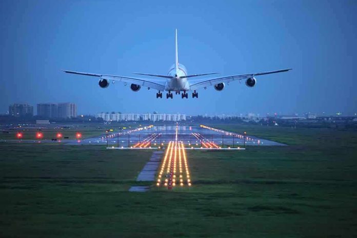 shutterstock_112881910 An airplane approaching the runway at night with landing lights illuminated