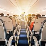 airplane cabin with passengers seated in economy class