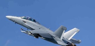 Twin-engine fighter jet climbing in a clear blue sky