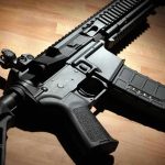 Black modern rifle on wooden surface