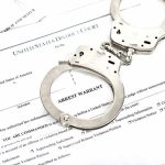 Handcuffs on arrest warrant documents
