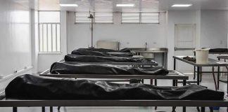 Mortuary room with covered bodies on metal gurneys