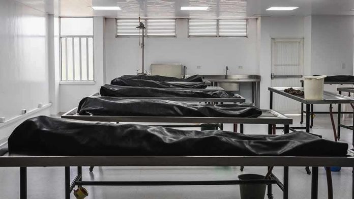 Mortuary room with covered bodies on metal gurneys