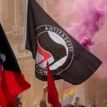 protesters with antifascist flags and purple smoke