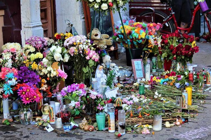 Memorial with flowers, candles, and tributes on a sidewalk