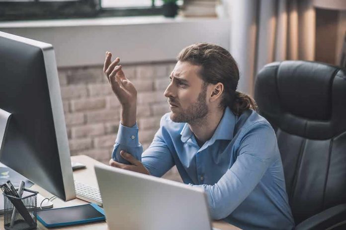 Man at desk looking frustrated at computer monitor