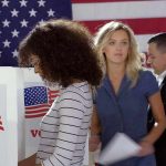 Voters at polling booths in front of an American flag