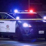 Police SUV with flashing lights at night behind yellow tape