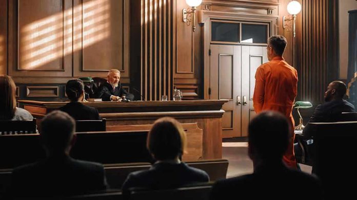 shutterstock_2056444847 Defendant in orange jumpsuit stands before judge in courtroom