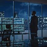 Sanctions Waived for Russia Oil—But Why? Trader in a dark office with multiple stock monitors and city skyline at night