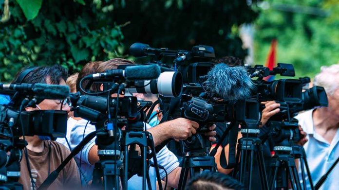 shutterstock_2210577723-3 TV news cameras crowding together at an outdoor event