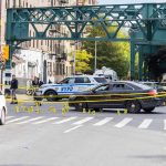 Police cars block a city intersection with yellow crime scene tape