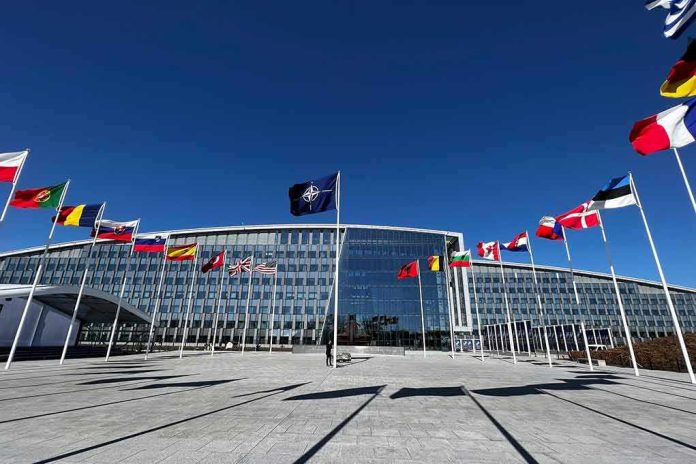 NATO headquarters with member flags in front under a clear blue sky