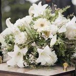 Slain CEO’s Uncle Has a Message for Luigi Mangione funeral casket with white flower arrangement