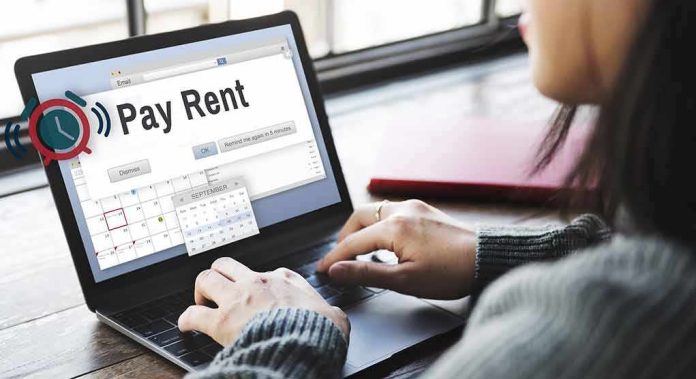 Person using a laptop with a rent reminder on screen