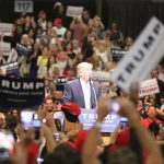 Why Trump Made the Crowd Raise Their Right Hands man at podium addressing a large crowd at a rally