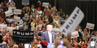 man at podium addressing a large crowd at a rally
