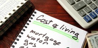 Budget notebook with cost of living list, calculator, and cash