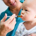 Surrogate Sued After Refusing to Abort Baby Baby taking liquid medicine from an oral syringe held by an adult