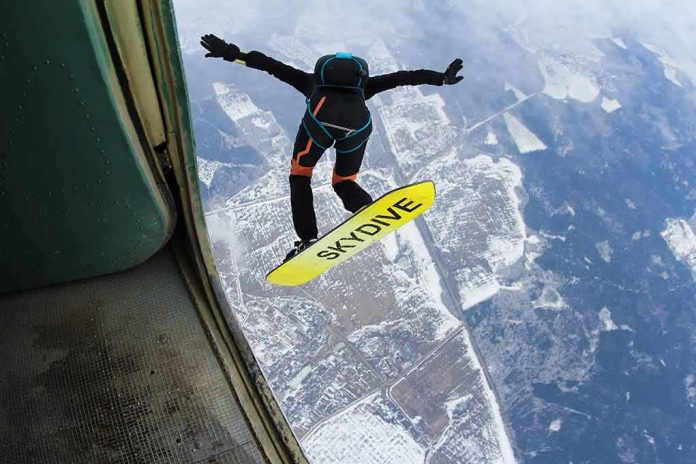 Skydiver jumps from plane with a skysurf board over snowy landscape