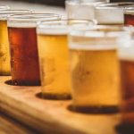 beer flight with assorted tasting glasses on a wooden tray