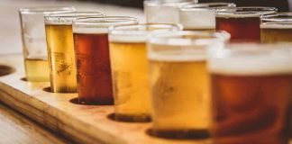 beer flight with assorted tasting glasses on a wooden tray