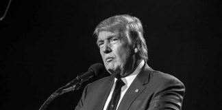 Donald Trump speaking at a microphone in a black-and-white photo