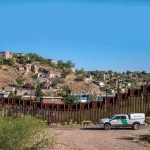 Judge Clears Way for Trump’s Border Wall Across Tribal Lands border fence with patrol truck in arid landscape