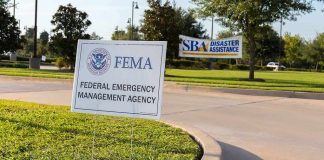 Ocean Water Is Pouring Into East Coast Streets FEMA sign on grassy median in a parking area