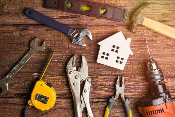 assorted hand tools around a house-shaped cutout on a wooden surface