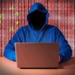 Hooded figure using a laptop