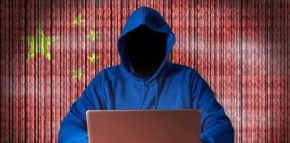 Hooded figure using a laptop