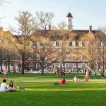 Students relaxing on a campus quad in front of a brick academic building