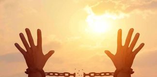 raised hands breaking chains against a sunset sky