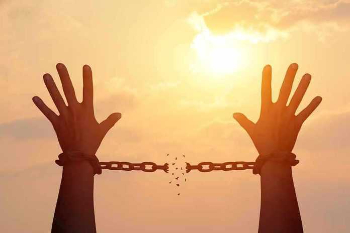 raised hands breaking chains against a sunset sky