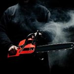 Person holding a red chainsaw in a dark, smoky setting