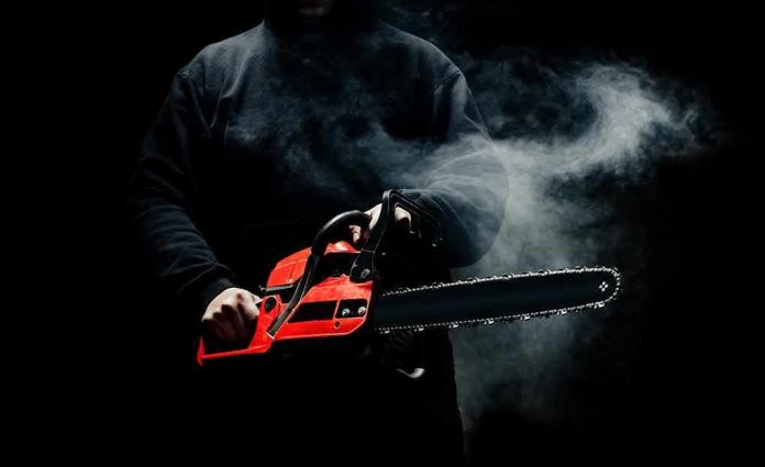 Person holding a red chainsaw in a dark, smoky setting