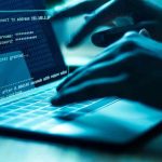 Hands typing on a laptop with cybersecurity login overlay