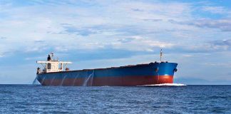 A large cargo ship sailing on the ocean under a blue sky