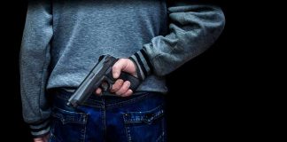 person holding a handgun behind their back
