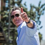 Newsom Caught on HIDDEN CAMERA man in sunglasses giving a thumbs-up outdoors